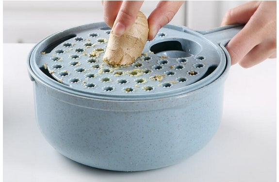 Mandoline slicer bowl with perforated grater lid, showing a peeled carrot being grated.