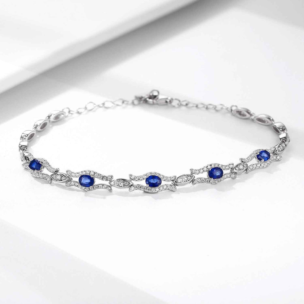 Silver tone tennis bracelet with blue oval gemstones set in a pavé style chain