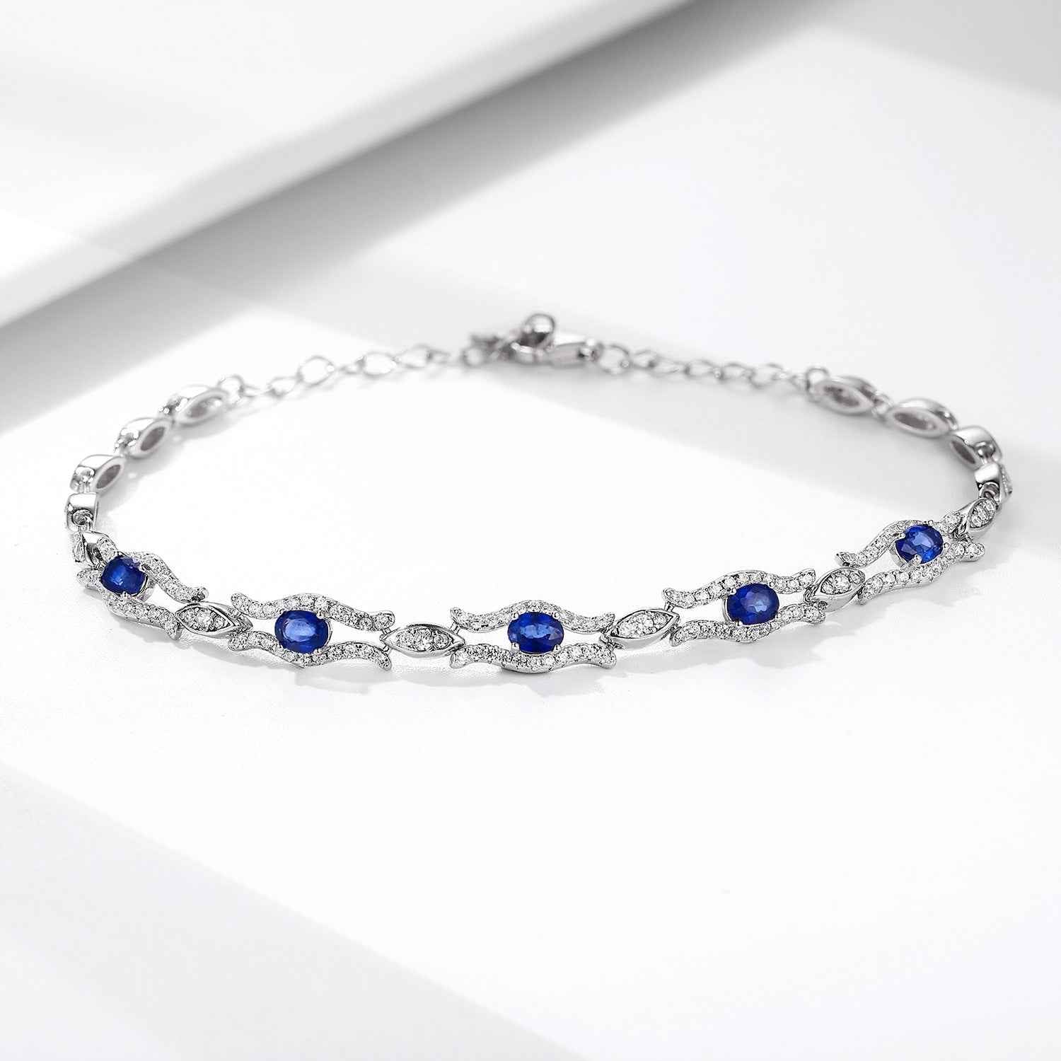 Silver tone tennis bracelet with blue oval gemstones set in a pavé style chain