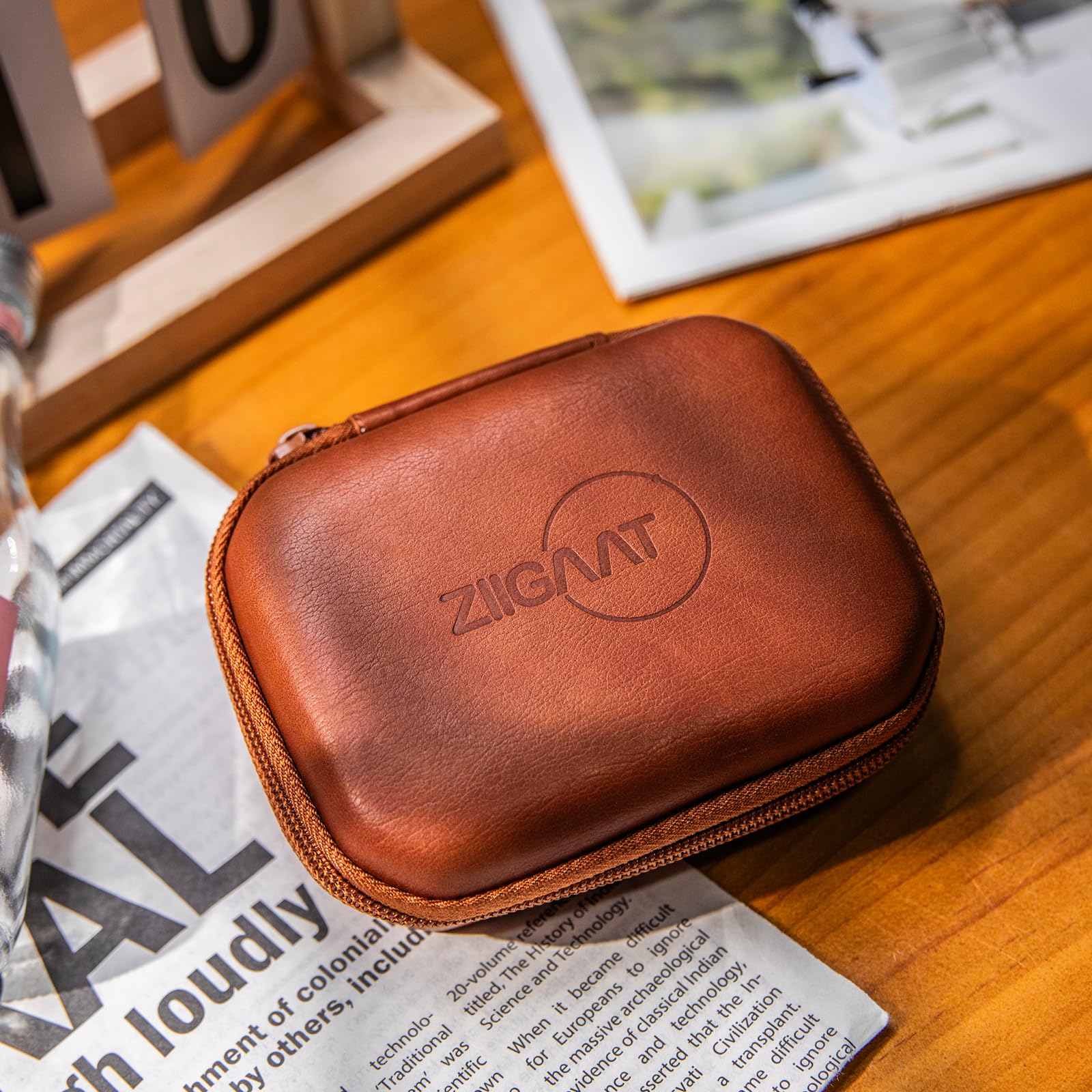 Brown leather earbud case with zipper and embossed ZiiGaaT logo, closed