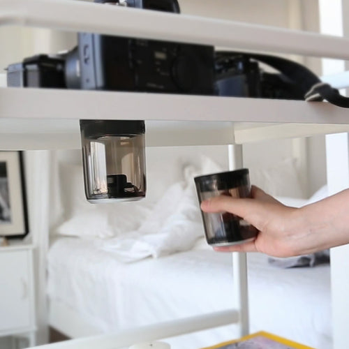 Bluetooth speaker pair with transparent bodies and black tops, held near a shelf