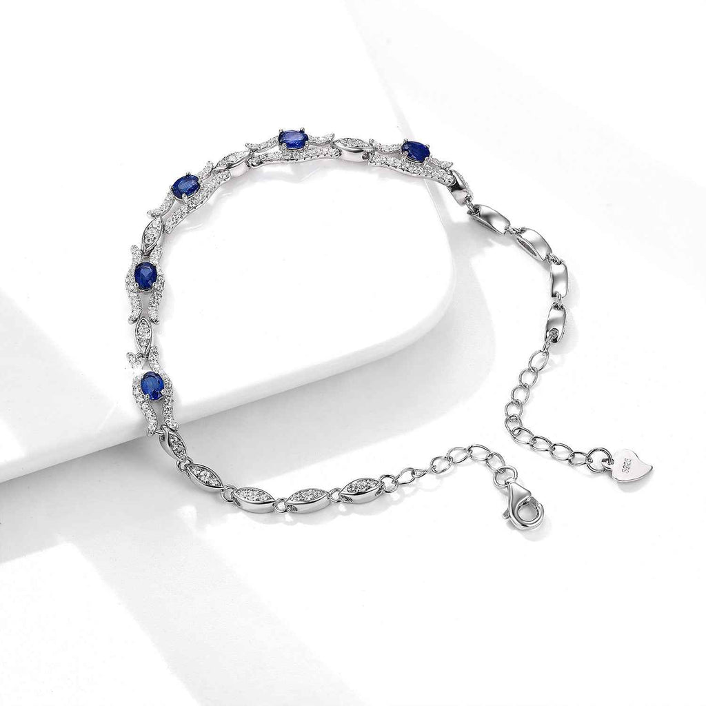 Silver tone sapphire bracelet with blue stones, chain extender, and small heart tag