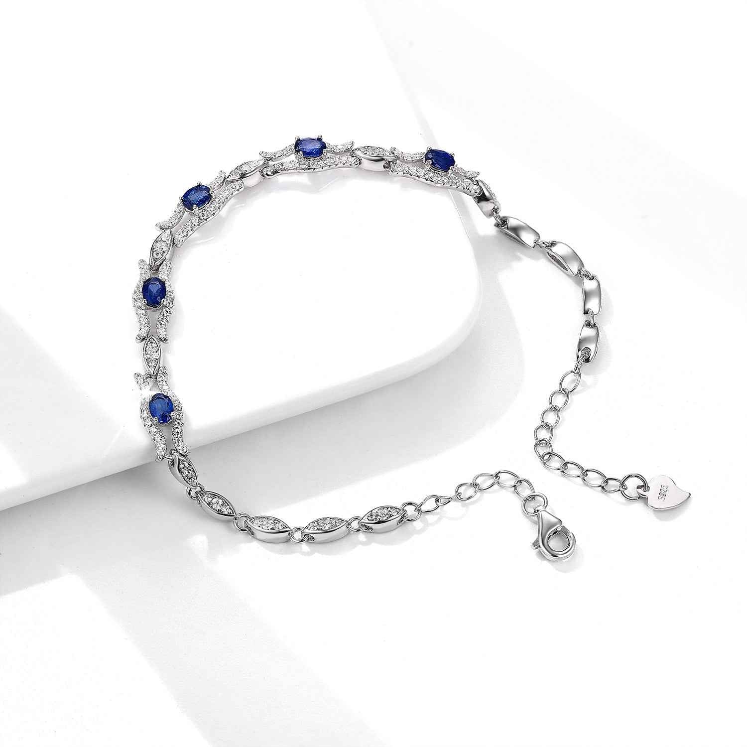 Silver tone sapphire bracelet with blue stones, chain extender, and small heart tag