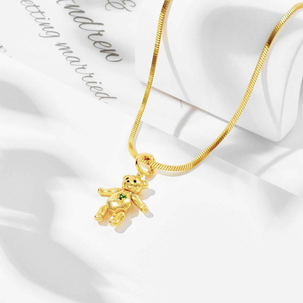 Gold snake-chain necklace with bear pendant charm and small green details