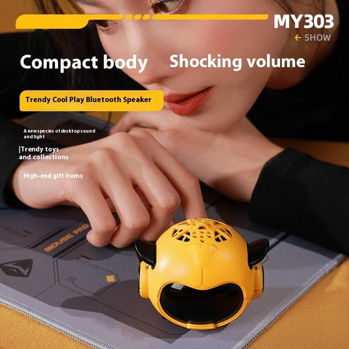 Yellow mini Bluetooth speaker on a mat, with cartoon face and side horn speakers