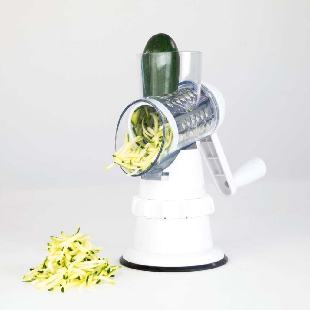 White manual vegetable slicer with grater drum feeding cucumber slices