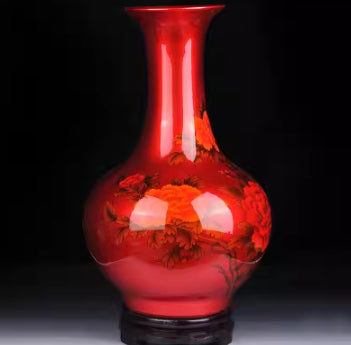Ceramic vase in red with floral motif and glossy black base.